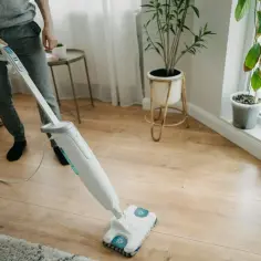 Osoba czyści panele podłogowe mopem parowym. Czy mop parowy nadaje się do paneli? Tak, ten model świetnie sobie radzi!