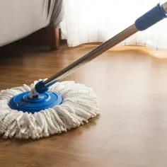 Mop na drewnianej podłodze, przygotowany do czyszczenia. Dowiedz się, jak przywrócić blask panelom podłogowym i cieszyć się ich naturalnym pięknem.