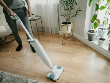 Osoba czyści panele podłogowe mopem parowym. Czy mop parowy nadaje się do paneli? Tak, ten model świetnie sobie radzi!