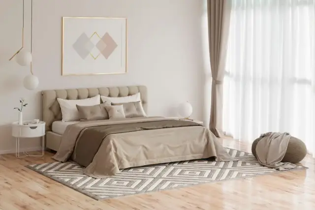 Elegancka sypialnia z łóżkiem, dywanem i drewnianymi podłogami do sypialni.