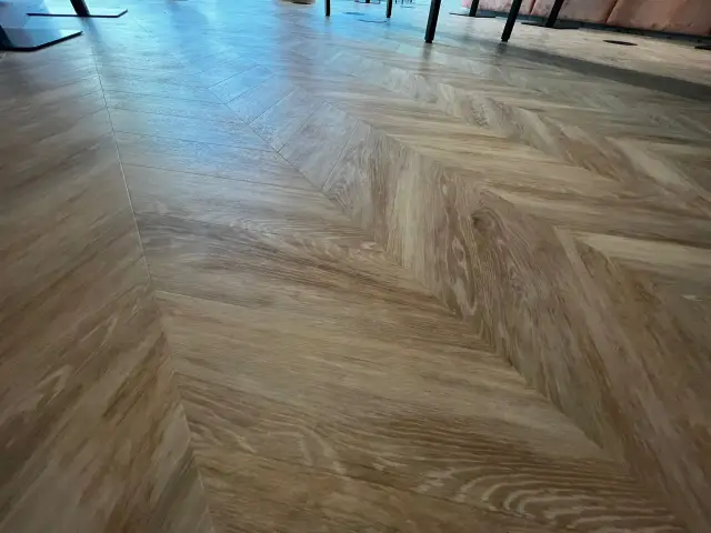 Drewniane podłogi do biura ułożone we wzór jodełki nadają wnętrzu elegancji i ciepła.